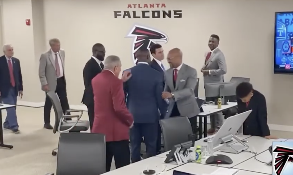 Falcons GM Terry Fontenot and Head Coach Raheem Morris hug owner Arthur Blank after selecting Michael Penix in the 2024 draft.